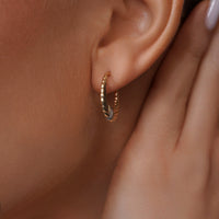 Load image into Gallery viewer, A model is styling with 14k Gold Two-Tone Ribbed Oval Hoop Earrings
