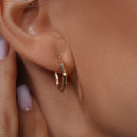 Load image into Gallery viewer, A Model Styling with 14k Gold Vintage Textured Oval Hoop Earrings
